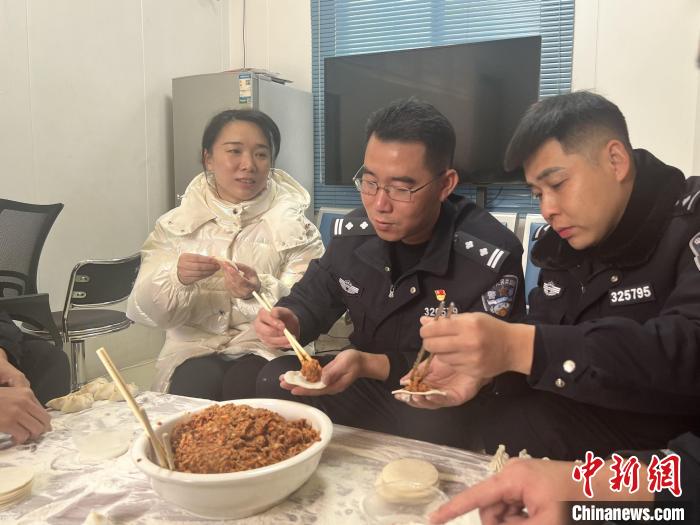 图为黄日夫妻正在和民警一齐包饺子。　高化雨 摄